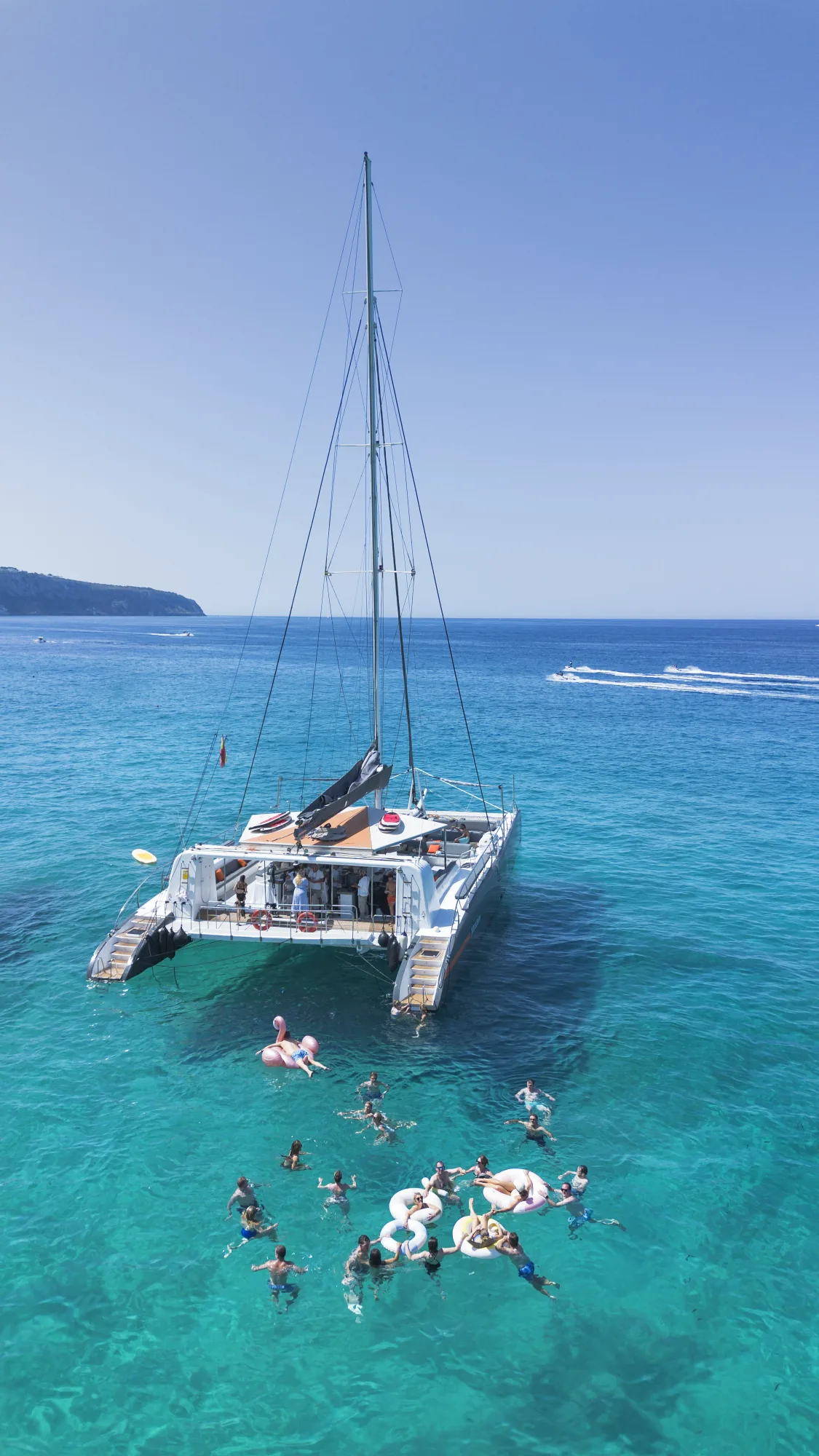 Aerial view of a catamaran and swimmers in turquoise water